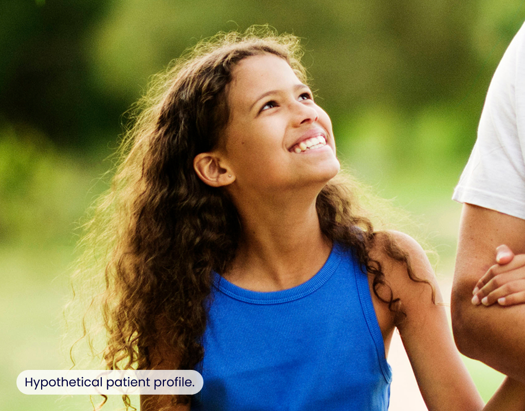 A young girl wrapping her hand around her dad's arm and smiling
