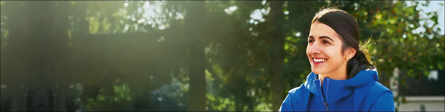 A woman wearing a blue windbreaker looking to the side and smiling